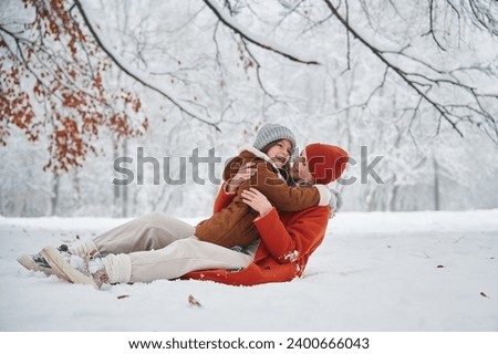 Lying down on the snow. Mother and her daughter is on the winter meadow and forest.