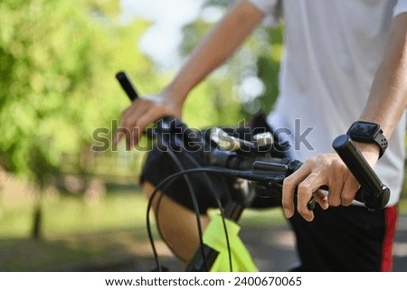 Happy retired man riding bicycle in the public park. Health care and wellbeing concept Royalty-Free Stock Photo #2400670065