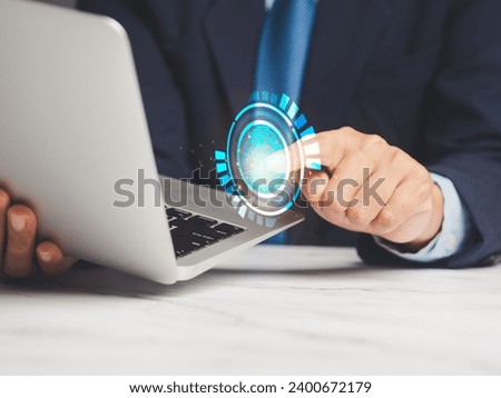Fingerprint scan provides security access with biometric identification. A businessman in a suit logged in to the system with a fingerprint on the virtual screen while sitting at a desk in the office