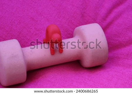 Little red mini hubby tests weightlifting with a pink dumbbell Royalty-Free Stock Photo #2400686265