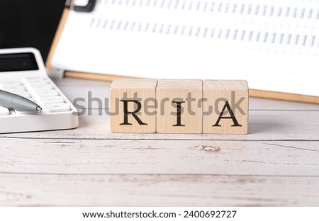 RIA word on wooden block with clipboard and calculator