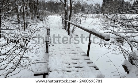 Wooden bridge across the river in winter Royalty-Free Stock Photo #2400693781