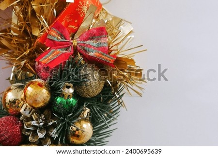 Part, details Christmas wreath of Christmas tree tinsel and Christmas tree balls, with cones in red, golden color close-up horizontally on a white background.  A handmade Christmas present in close-up