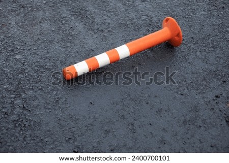 A parking pole fell on the asphalt. Parking details. Traffic limiter. Orange Stick.