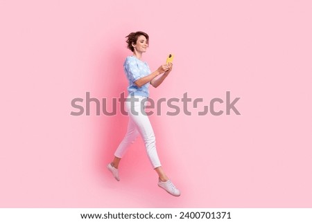 Full size profile photo of excited nice girl jump use smart phone empty space ad isolated on pink color background