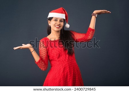 Portrait of a young girl presenting something on hand with a happy smiling face. christmas concept 