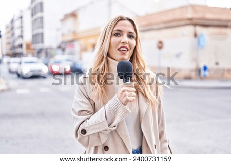 Young blonde woman reporter working using microphone at street