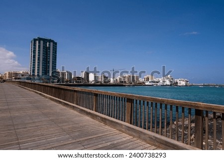 View of the city of Arrecife from the islet, from a wooden bridge. Turquoise blue water. Sky with big white clouds. Seascape. Lanzarote, Canary Islands, Spain.