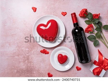 Valentines day. heart shaped glazed valentine cake, gift and wine on pink concrete background Royalty-Free Stock Photo #2400740731