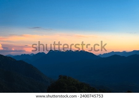 Beautiful natural scenery mountain peaks in the sunset on the hills and the Thai language on the sign means Glosselo Viewpoint at Mae Hong Son, Thailand. Space for Background and Wallpaper concept.