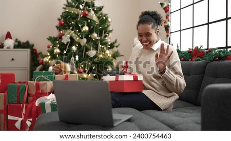 African american woman unpacking gift having video call at home