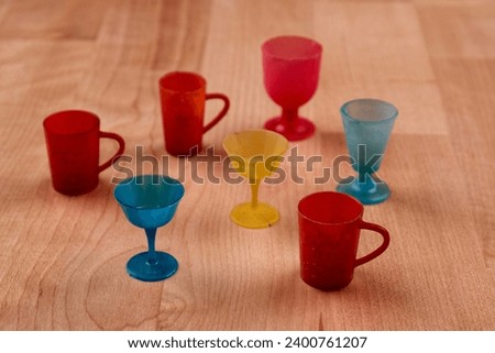 a set of colored plastic toy cups standing on a wooden table, close up image