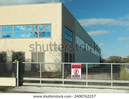 Sign with text Restricted Area Authorized Person Only on fence near factory building outdoors
