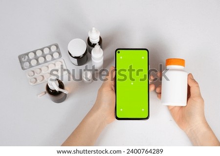 Green screen chroma key smartphone in the hands of patient or doctor and a lot of medicines. Medicine, instructions for use
