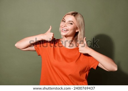 Photo portrait of attractive young woman showing thumb up dressed stylish orange clothes isolated on khaki color background