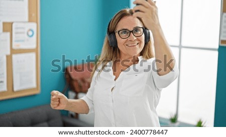 Middle age hispanic woman business worker make selfie picture by smartphone at the office