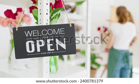 Signboard "Open" on the glass door at flower shop. Text on black signboard "Welcome Open" at flower shop. Small business. Opening store. Starting workday