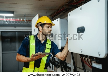 Technician Engineering setting inverter solar panel in electrical room. Service engineer installing solar cell on the roof of factory. Clean and Renewable energy concept. Royalty-Free Stock Photo #2400792423