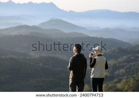 Tourist couple drinking coffee Admire the mountainside scenery as the sun rises in the morning.