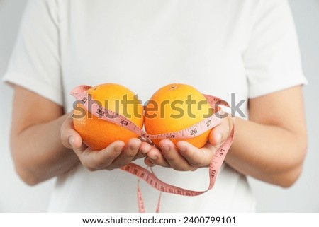 Hand holding fresh organic orange fruit and measure tape.