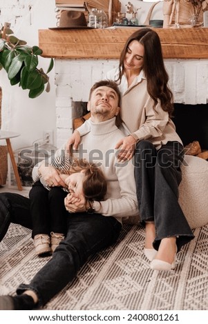 Happy family day. Young loving parents, mom and dad tickle adorable little child daughter, having fun, embracing and laughing at cozy Scandinavian living room at home.Parenthood and childhood concept.