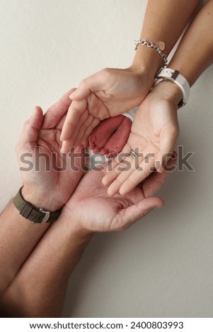 The palms of the parents, father and mother hold the legs, feet of a newborn baby in a white wrapper on a white background. Feet, heels and toes of a newborn child close -up. Professional macro photo.