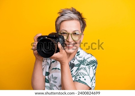 Photo portrait of lovely grandma hold professional camera wear trendy tropical print garment isolated on yellow color background