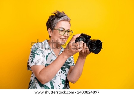 Photo portrait of lovely grandma hold camera watch cadres photos dressed stylish tropical print garment isolated on yellow color background