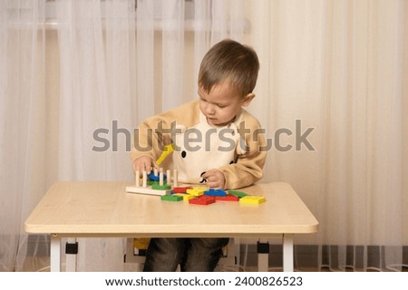 A two-year-old boy plays with wooden toys to develop logic and motor skills