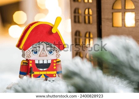 A toy soldier Nutcracker and walnuts on a Christmas background with a garland. Tchaikovsky's ballet. Christmas New Year card 2024.