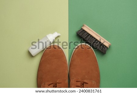 Suede shoes with brush and foam bottle on green background. Shoe care Royalty-Free Stock Photo #2400831761