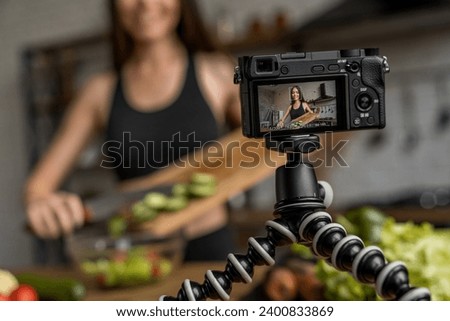 Cheerful woman cooking fresh salad in kitchen and recording video lesson for followers on social media. streaming on live. Veganism and vegetarianism, raw eating habits