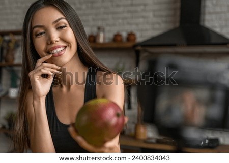 Young sport female recording video about food on mounted camera in kitchen. Meal healthy eating habits blogging vlogging, recording on live stream online. Weight loss