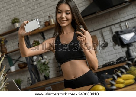 Asian woman healthy blogger making selfie with avocado in front of the camera recording vlog video at home doing taking selfie, videocall, talking about healthy eating habits