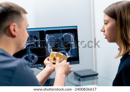 the radiologist doctor looks at the screen on which the 3D image of the nose scan shows the patient what needs be changed during surgery