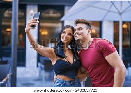 Man and woman couple smiling confident make selfie by smartphone at coffee shop terrace