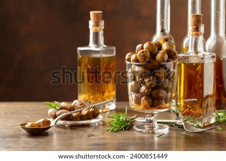 Spicy olives and bottles of olive oil. Preserved olives, bottles of olive oil, and rosemary twigs on a wooden table. Copy space.