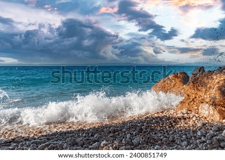 Sea surf. Picturesque seashore with a stone beach at sunset.