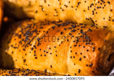 Close up on details of sausages baked in dough sprinkled with salt and poppy seeds. Sausages rolls, delicious homemade pastries.