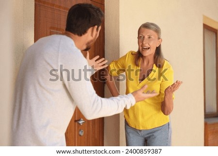 Emotional neighbours having argument near house outdoors Royalty-Free Stock Photo #2400859387