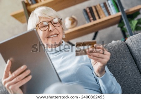 Cheerful senior caucasian woman using digital tablet and credit card for shopping online. E-commerce, e-banking, bank account debt, mortgage, pension receiving. Cashless payment Royalty-Free Stock Photo #2400862455