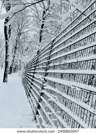 Perspective view of a snowy metal fence. Winter park landscape. Nice picture.
