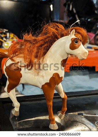 Plastic horse toy with curly hair stand at the table 