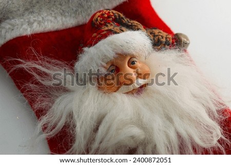 A close up photo of a red Santa Christmas themed stocking on a white desk. 