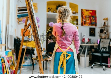 Color painting for disabled kids, child who are down syndrome and student teacher, development of children with special needs. Rear view of little girl in the art workshop.