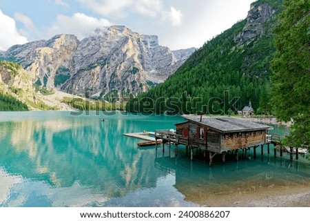 Sunset view over Lake Braies or Pragser Wildsee in the Dolomites, one of the most beautiful lakes in Italy. Boats in the middle of the lake surrounded by mountains. Travel and leisure.