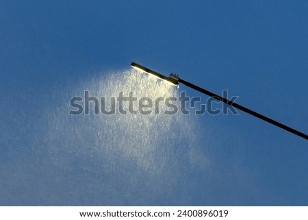 A street lamp in selective focus shines in a snowfall, blizzard, storm on a winter night.Picture for weather forecast.