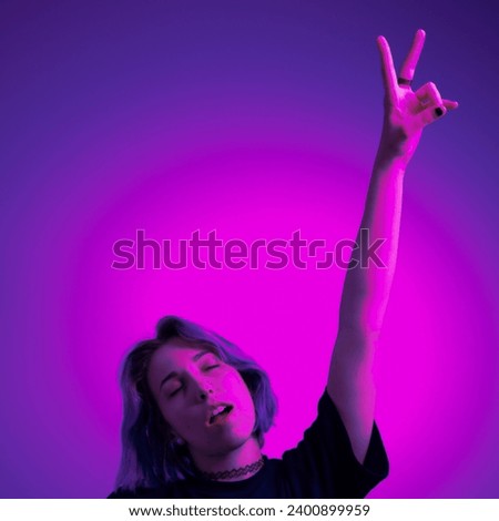 Young Woman with Raised Arm Making a Peace Sign with Hand on Brightly Colored Background