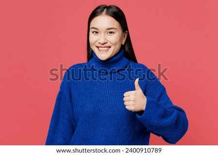 Young smiling happy cheerful woman of Asian ethnicity she wearing blue sweater casual clothes showing thumb up like gesture isolated on plain pastel pink background studio portrait. Lifestyle concept Royalty-Free Stock Photo #2400910789