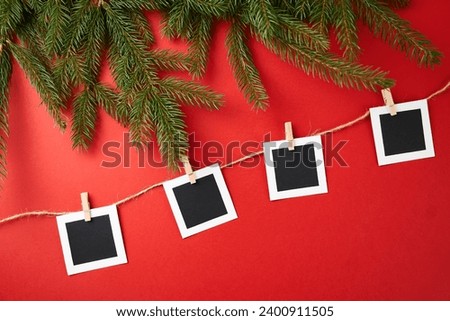 Layout of square photos on a red background. Christmas tree branches on the side of the frame. Concept of New Year holidays.